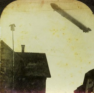 Stereopticon image of a WW-1 dirigible passing over a German town