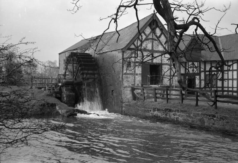 A view of the exterior of Erbistock Mill, clearly showing the water wheel on the left. The original caption states that the mill was built in 1661, and that the exterior is typical of seventeenth century mills.