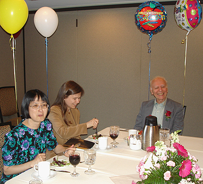 photograph of teachers eating cake with balloons tied to their chair